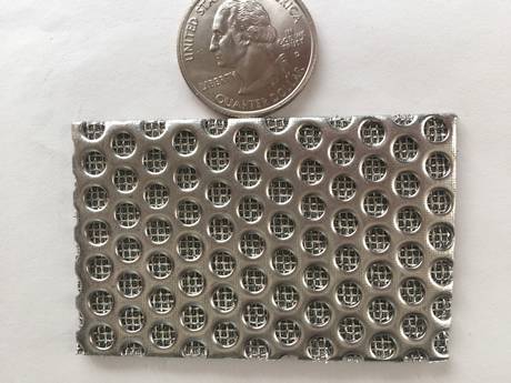 A piece of stainless steel perforated metal sintered filter mesh panel and a coin on the gray background.