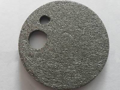 A filter disc made from iron-chromium-aluminum fiber felt with a big hole and a small one.