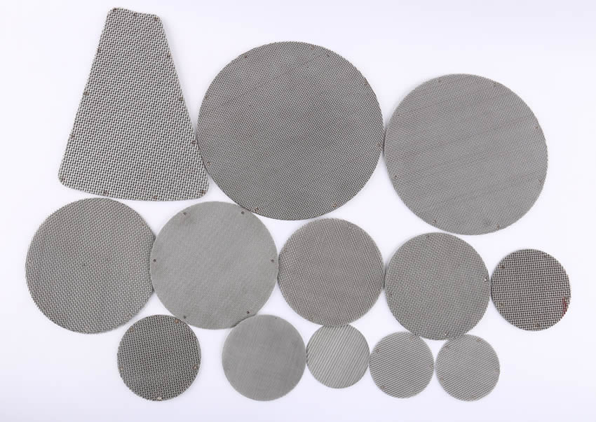 Several sintered filter discs in different diameters and shapes on the gray background.